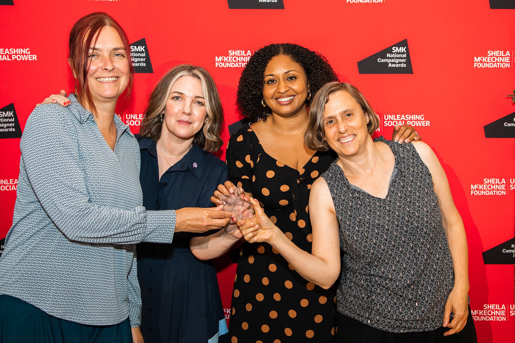 Photo of four smiling women collecting an award
