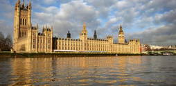 The House of Parliament against a blue and cloudy sky. In shot is the River Thames.