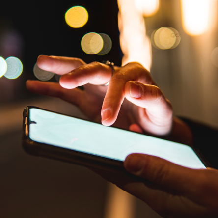 A young white person can be seen using a mobile phone. Only their hands are visible.