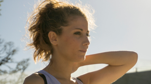 A young woman looks serious as she stands in the sunshine.